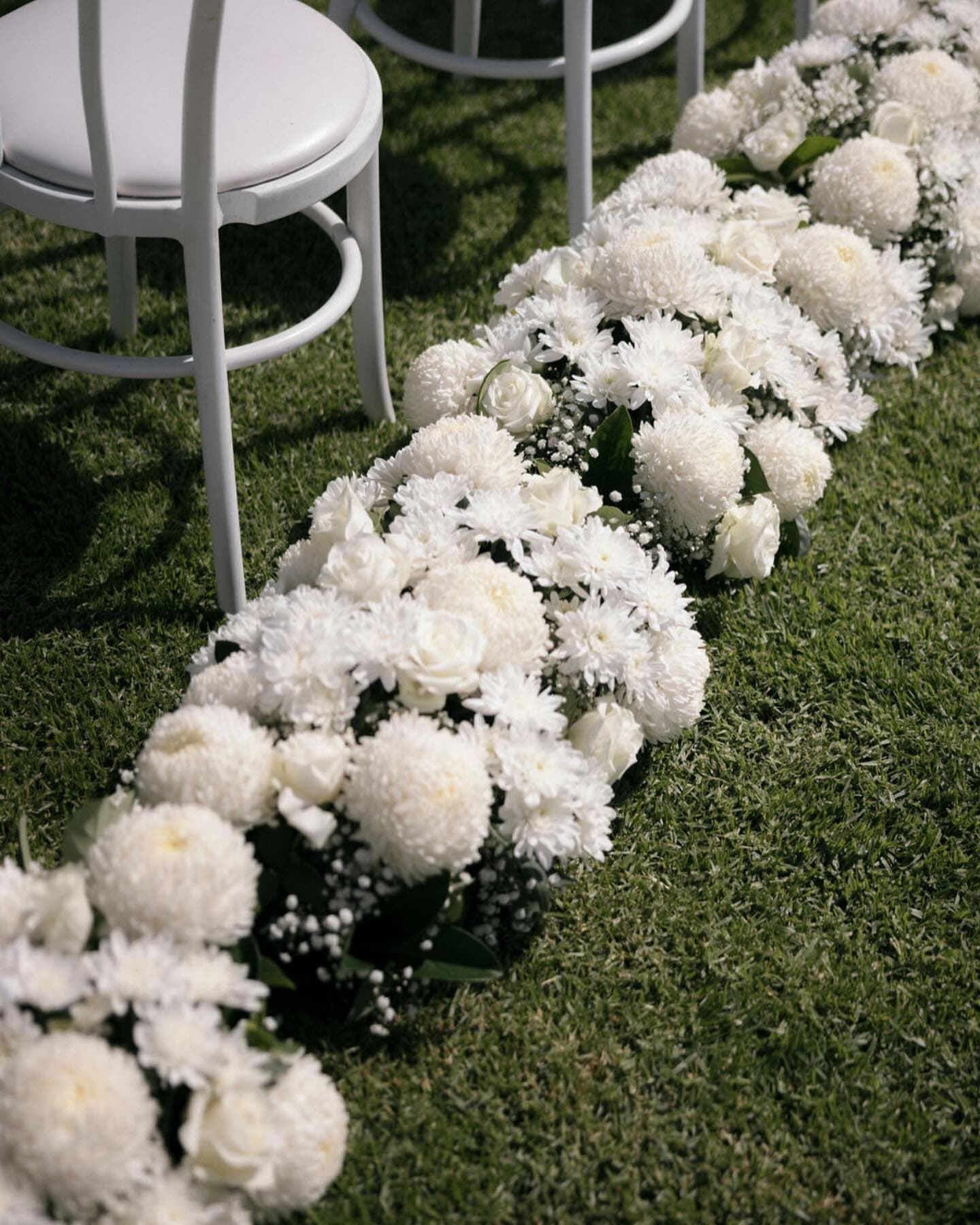 Wide view of garden ceremony with white florals lining the aisle